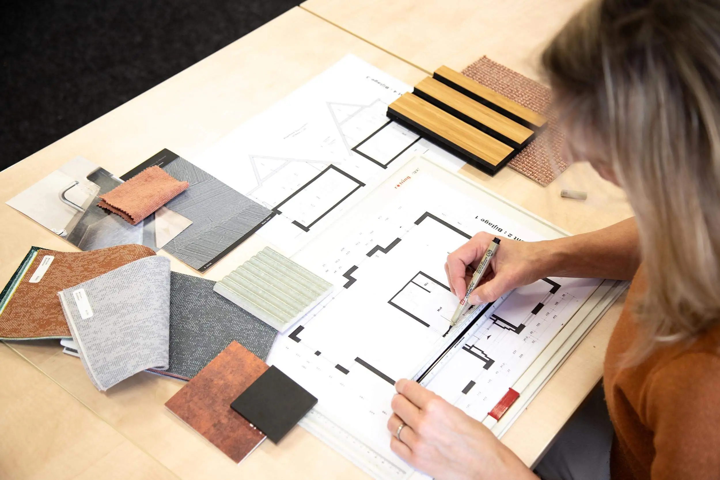 Interieurontwerper met plattegrond van ruimte aan het schetsen met naast haar kleurstalen.