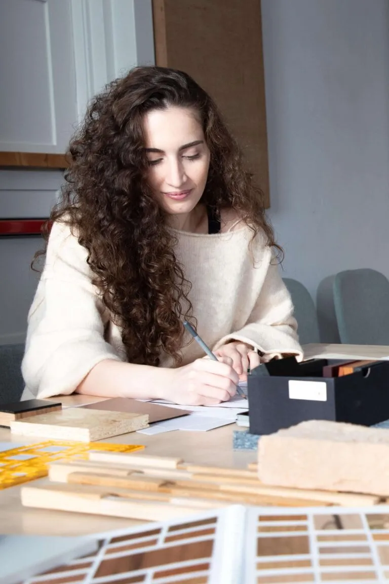Cursist van korte opleiding Starten als Ondernemer, druk met opdrachten uitwerken aan tafel die vol ligt met stalen.